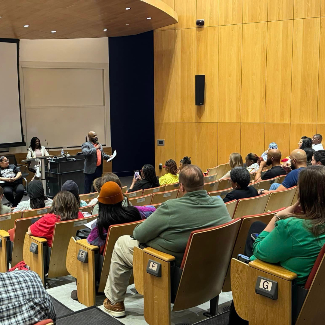 Attendees in a lecture hall watch speakers at the Austin event