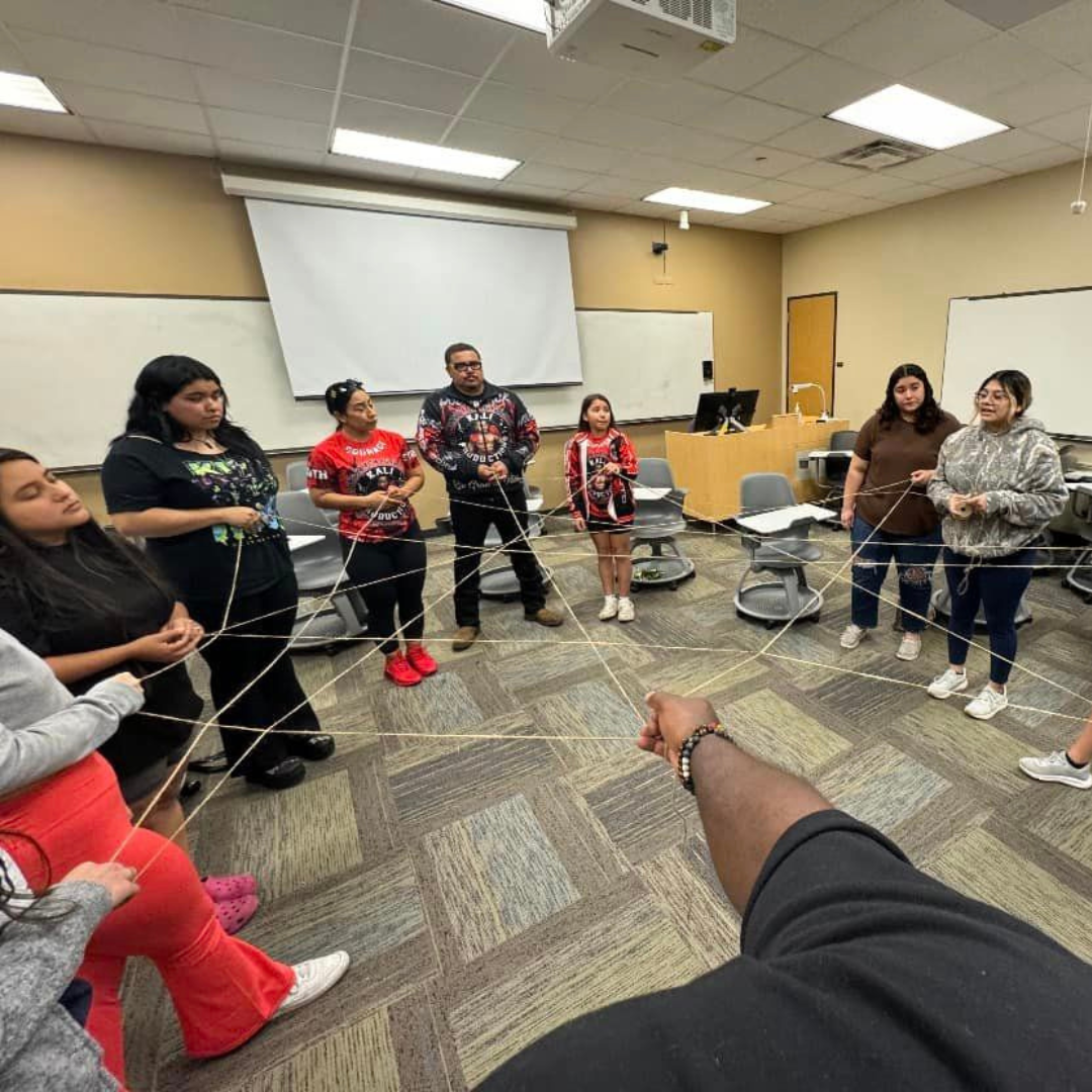 Event attendees participate in an activity with strings stretched across a circle of people